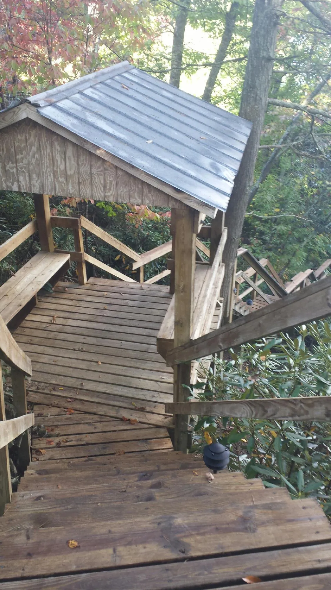 Metal roofed shelter over wooden steps on a wooded walkway — Skylight Repair & Installation work by our crew in Jamaica